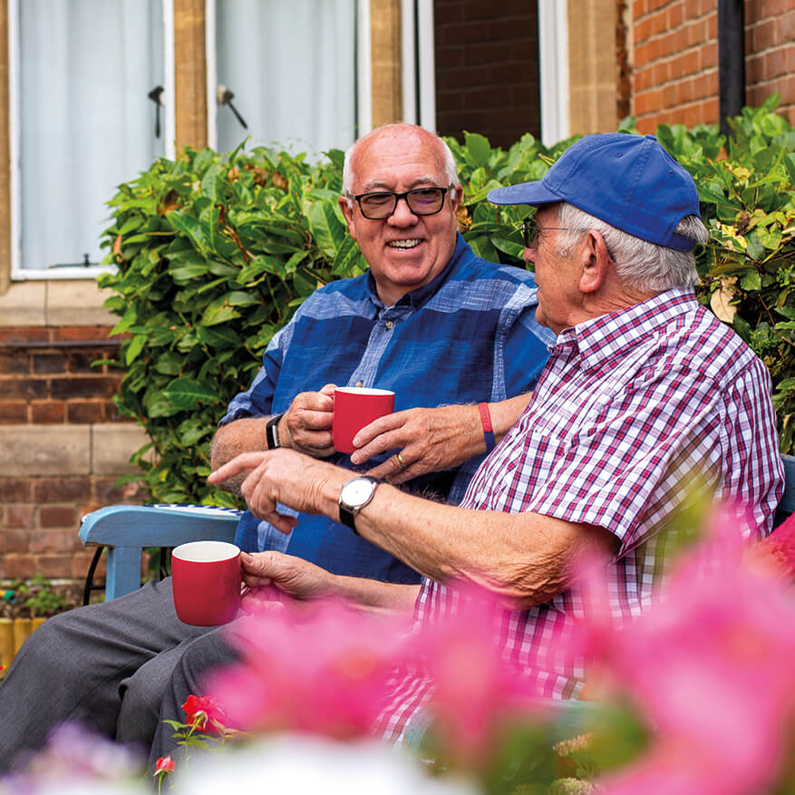 Service users enjoy a cup of tea in the garden of one of our Older People services