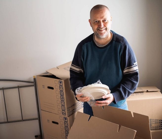 Robert moves into his new home and smiles as he unpacks his things